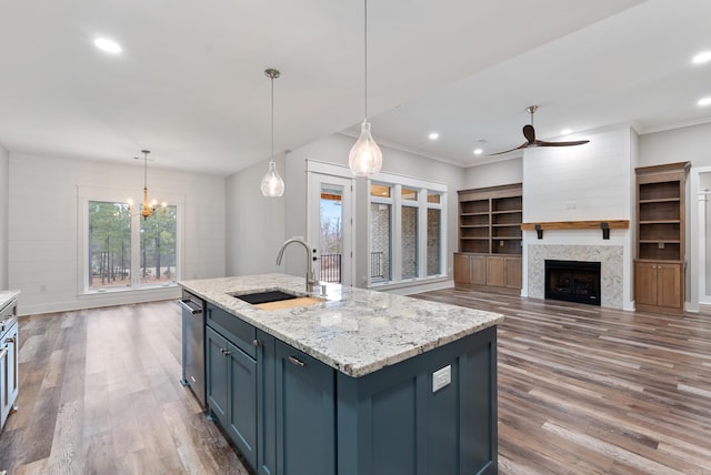 kitchen with hanging light fixtures, sink, blue cabinetry, and a center island with sink