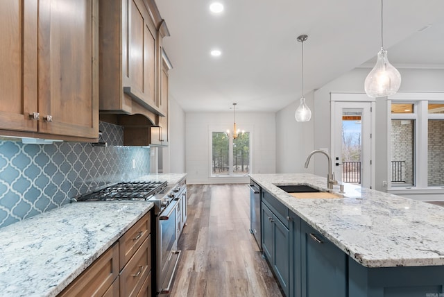 kitchen featuring a spacious island, sink, light stone counters, hanging light fixtures, and stainless steel appliances