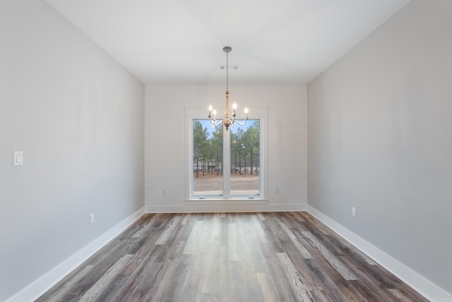 unfurnished dining area featuring dark wood-type flooring and a chandelier