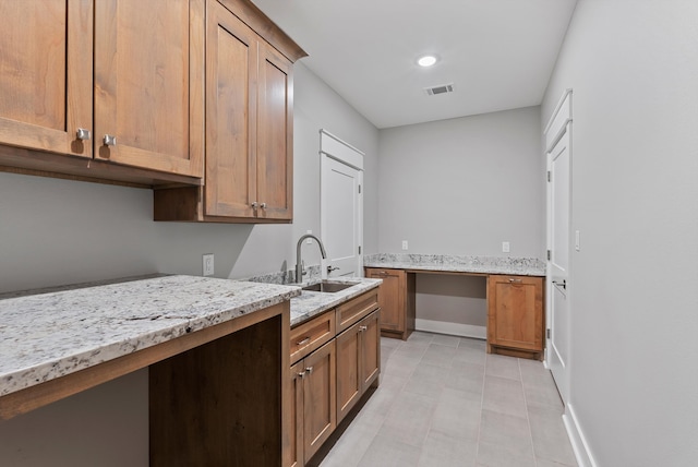 kitchen featuring light stone counters and sink