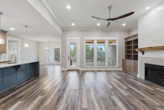 unfurnished living room featuring dark hardwood / wood-style flooring, sink, ornamental molding, and a tile fireplace