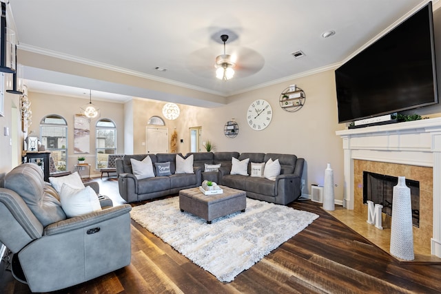 living room featuring a tile fireplace, crown molding, ceiling fan, and dark hardwood / wood-style flooring