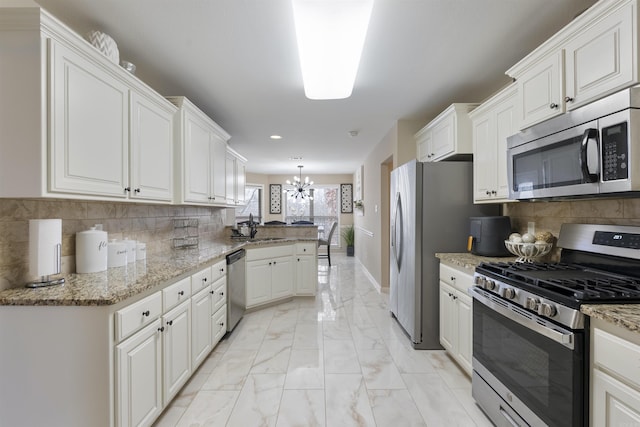 kitchen with light stone counters, appliances with stainless steel finishes, kitchen peninsula, and white cabinets