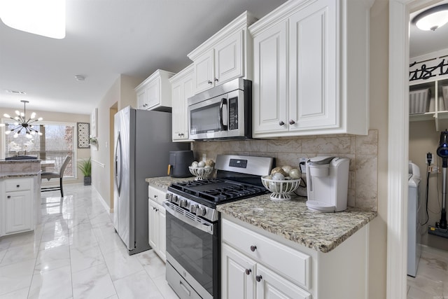 kitchen featuring white cabinetry, backsplash, stainless steel appliances, light stone counters, and washer / clothes dryer