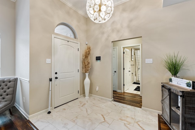 entryway with crown molding, an inviting chandelier, and a high ceiling