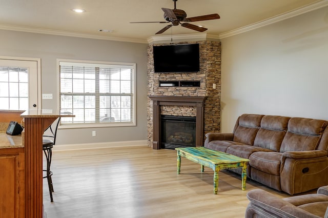 living room with light hardwood / wood-style flooring, a fireplace, ornamental molding, and ceiling fan