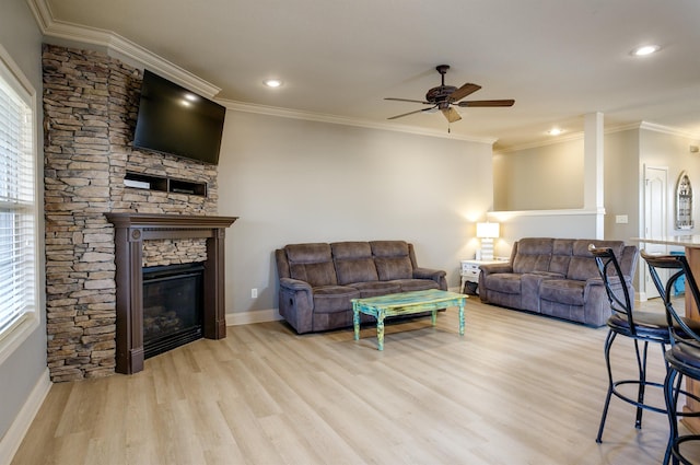 living room featuring crown molding, ceiling fan, a fireplace, and light hardwood / wood-style flooring