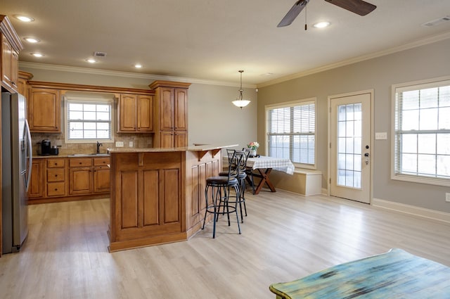 kitchen with backsplash, hanging light fixtures, a center island, stainless steel refrigerator with ice dispenser, and light hardwood / wood-style flooring