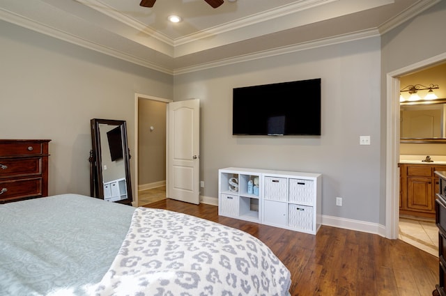 bedroom featuring dark wood-type flooring, sink, crown molding, a tray ceiling, and ceiling fan