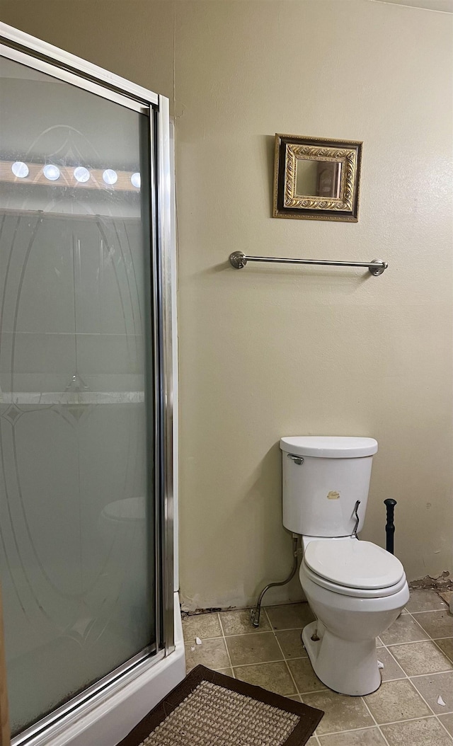 bathroom featuring tile patterned floors, toilet, and a shower with shower door