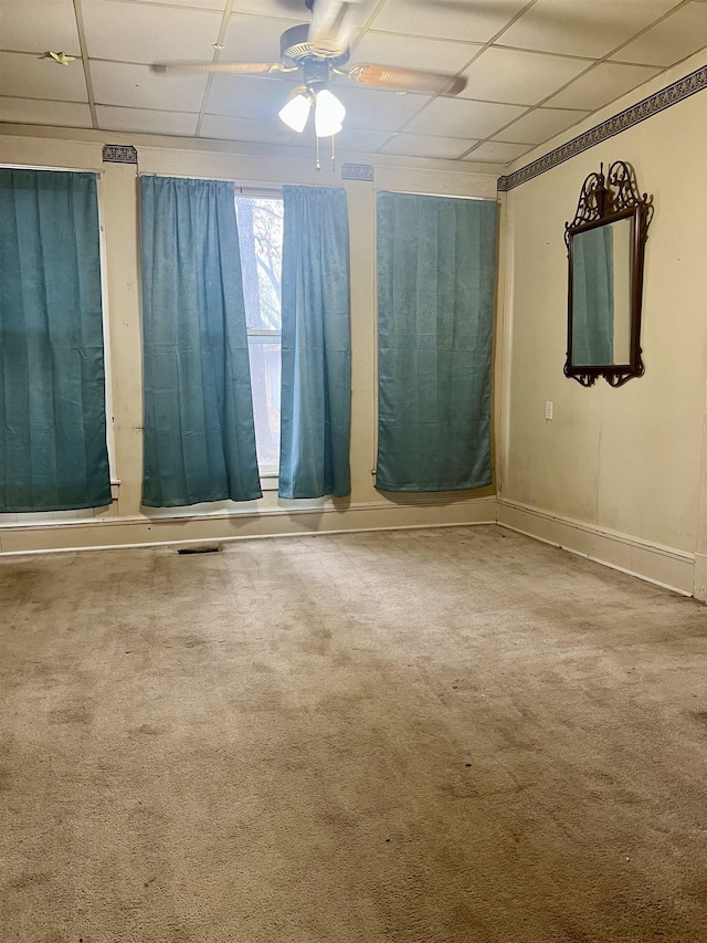 carpeted spare room featuring ceiling fan and a drop ceiling