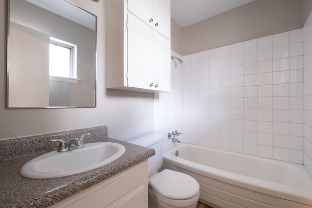 full bathroom featuring tiled shower / bath, vanity, and toilet