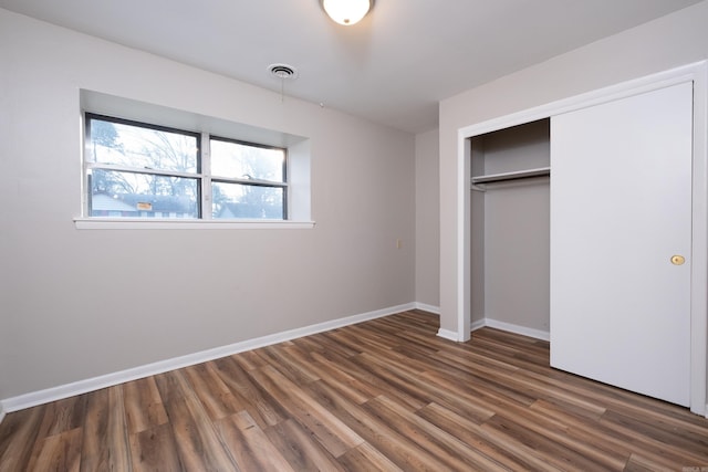 unfurnished bedroom with dark hardwood / wood-style flooring and a closet