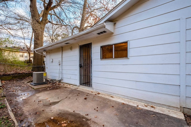 view of exterior entry with a patio and central air condition unit