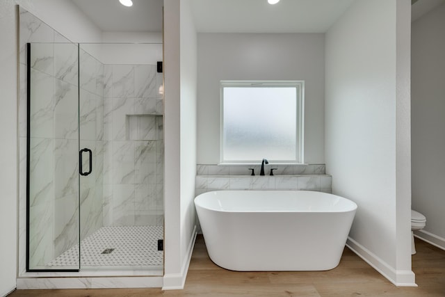 bathroom featuring wood-type flooring, toilet, and separate shower and tub