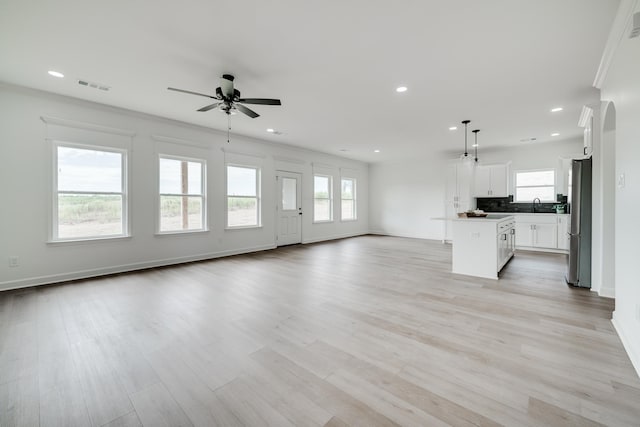 unfurnished living room featuring ceiling fan, sink, and light hardwood / wood-style flooring