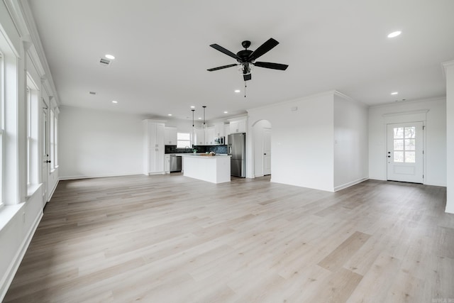 unfurnished living room with ceiling fan, ornamental molding, and light hardwood / wood-style flooring