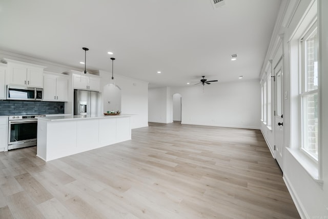 kitchen with white cabinetry, tasteful backsplash, a center island, appliances with stainless steel finishes, and pendant lighting