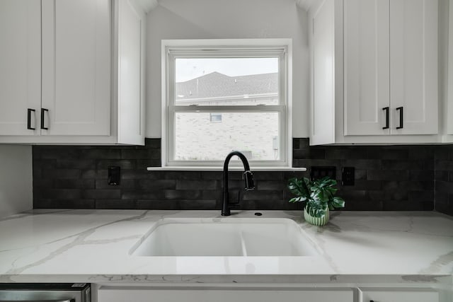 kitchen with light stone countertops, sink, white cabinets, and decorative backsplash