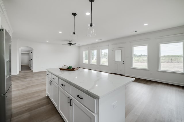 kitchen featuring white cabinetry, light stone counters, a center island, hanging light fixtures, and high quality fridge