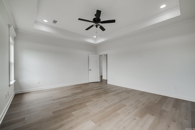 unfurnished room featuring crown molding, a tray ceiling, ceiling fan, and light wood-type flooring