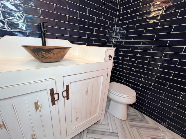 bathroom with vanity, tile walls, and toilet