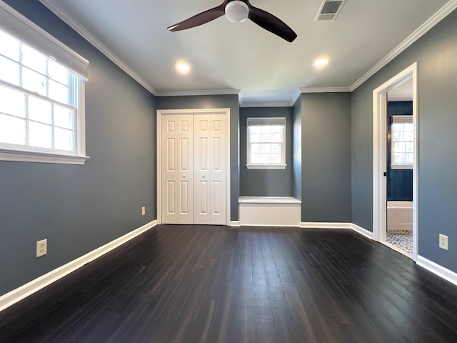 unfurnished bedroom with multiple windows, crown molding, dark wood-type flooring, and a closet