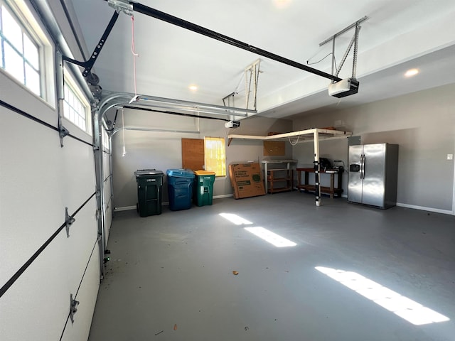 garage with a garage door opener and stainless steel refrigerator with ice dispenser