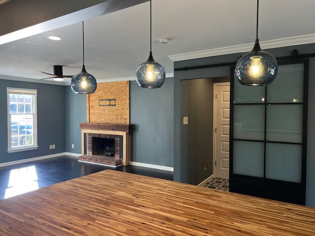 unfurnished living room featuring crown molding, wood-type flooring, a fireplace, and a barn door