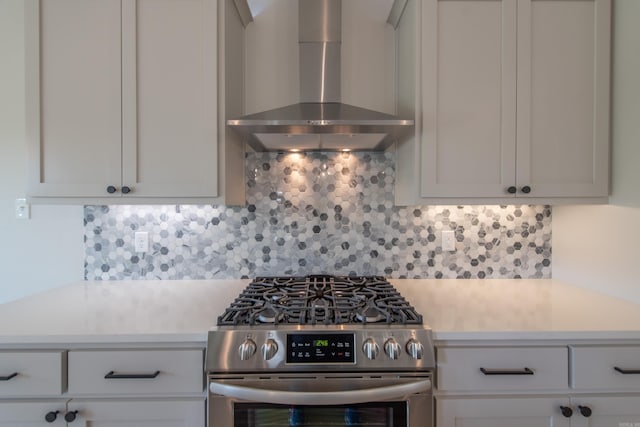 kitchen with white cabinets, gas stove, decorative backsplash, and wall chimney range hood