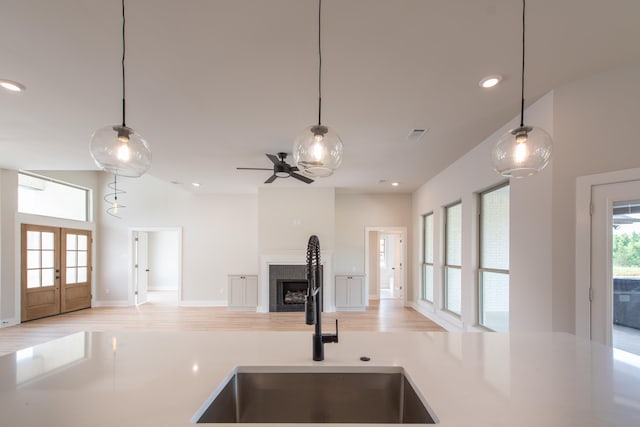 kitchen with french doors, sink, decorative light fixtures, vaulted ceiling, and light hardwood / wood-style floors