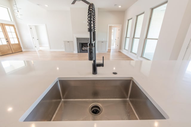 details featuring french doors, light hardwood / wood-style floors, sink, and a tile fireplace