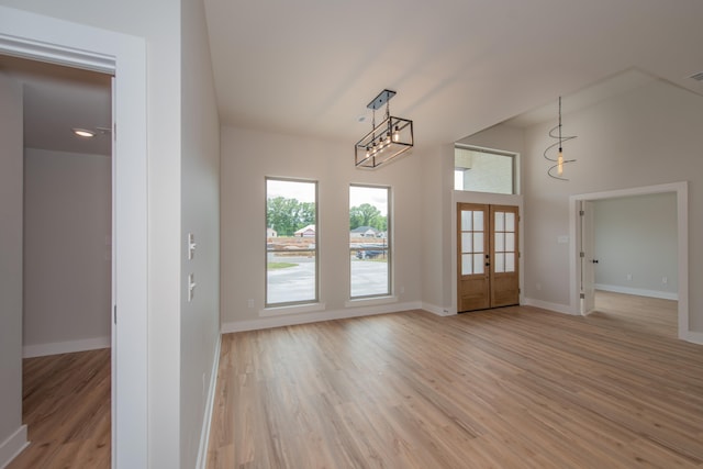 entrance foyer with french doors, light hardwood / wood-style flooring, and a high ceiling