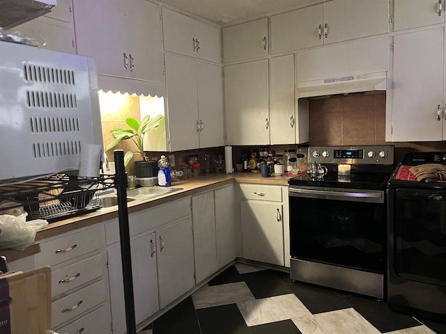 kitchen featuring stainless steel electric range oven, washing machine and clothes dryer, sink, and white cabinets