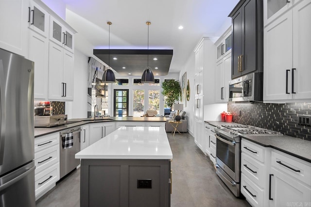 kitchen with sink, white cabinetry, hanging light fixtures, stainless steel appliances, and a center island