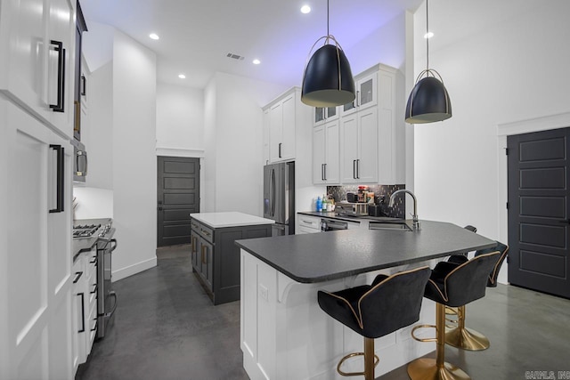 kitchen featuring sink, white cabinetry, hanging light fixtures, stainless steel appliances, and a kitchen breakfast bar