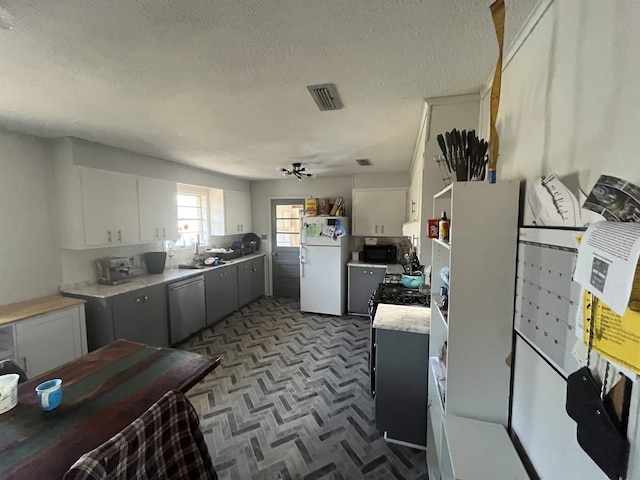 kitchen with dishwasher, sink, white cabinets, white refrigerator, and a textured ceiling