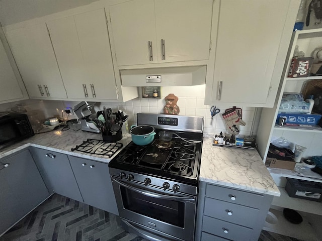 kitchen featuring tasteful backsplash, light stone counters, stainless steel range with gas cooktop, and ventilation hood