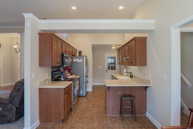 kitchen featuring a breakfast bar, sink, ornamental molding, appliances with stainless steel finishes, and kitchen peninsula