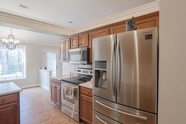 kitchen with appliances with stainless steel finishes, hanging light fixtures, light tile patterned floors, crown molding, and an inviting chandelier