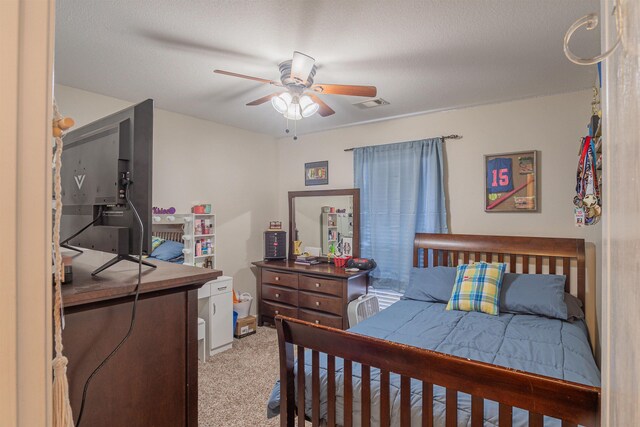 bedroom featuring ceiling fan, light colored carpet, and a textured ceiling