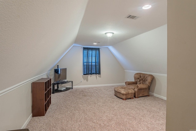 sitting room with vaulted ceiling, carpet floors, and a textured ceiling