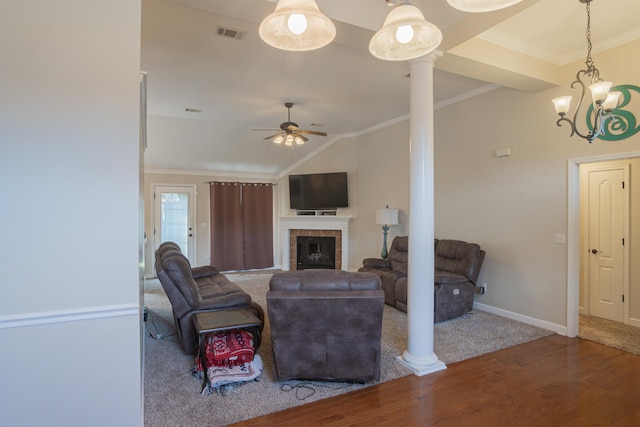 living room featuring a tiled fireplace, crown molding, and ornate columns