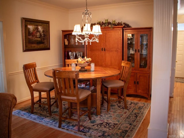 dining area with crown molding, hardwood / wood-style floors, and an inviting chandelier