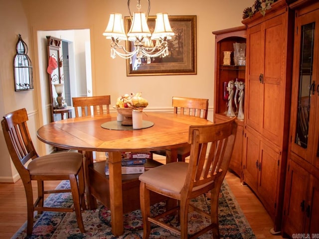 dining space with an inviting chandelier and light hardwood / wood-style flooring