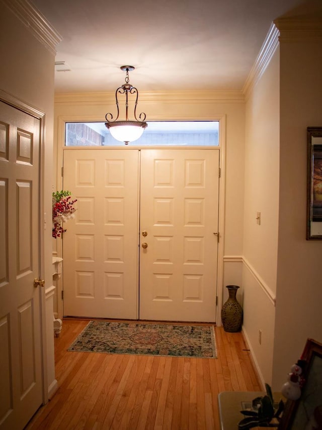 entrance foyer with ornamental molding and light hardwood / wood-style flooring