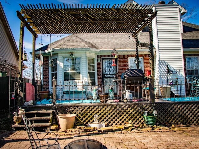 rear view of property featuring a pergola and a fire pit