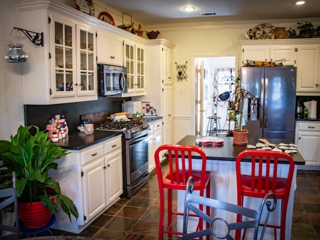 kitchen with crown molding, a breakfast bar, white cabinets, and appliances with stainless steel finishes