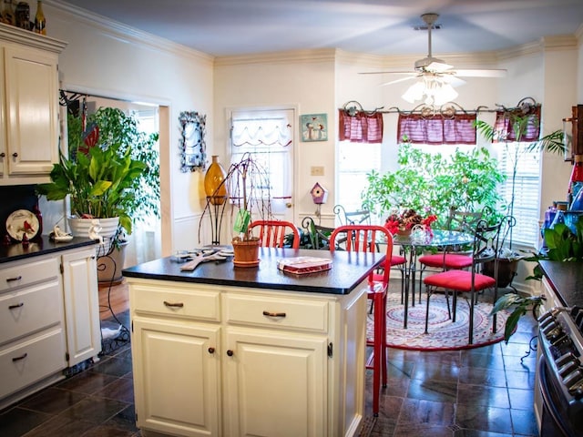 kitchen featuring ornamental molding, a center island, stainless steel stove, and a wealth of natural light