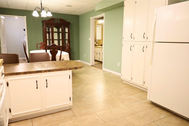 kitchen featuring an inviting chandelier, white fridge, white cabinets, pendant lighting, and a drop ceiling